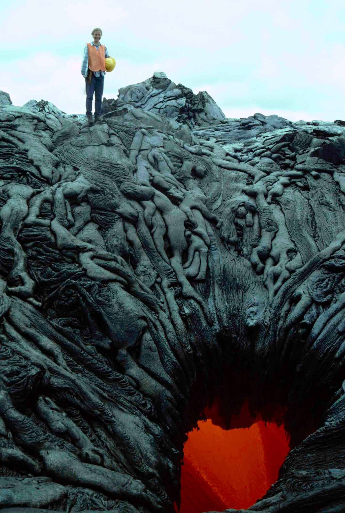 A scientist standing on top of lava tubes that sink into an infernal hellhole below